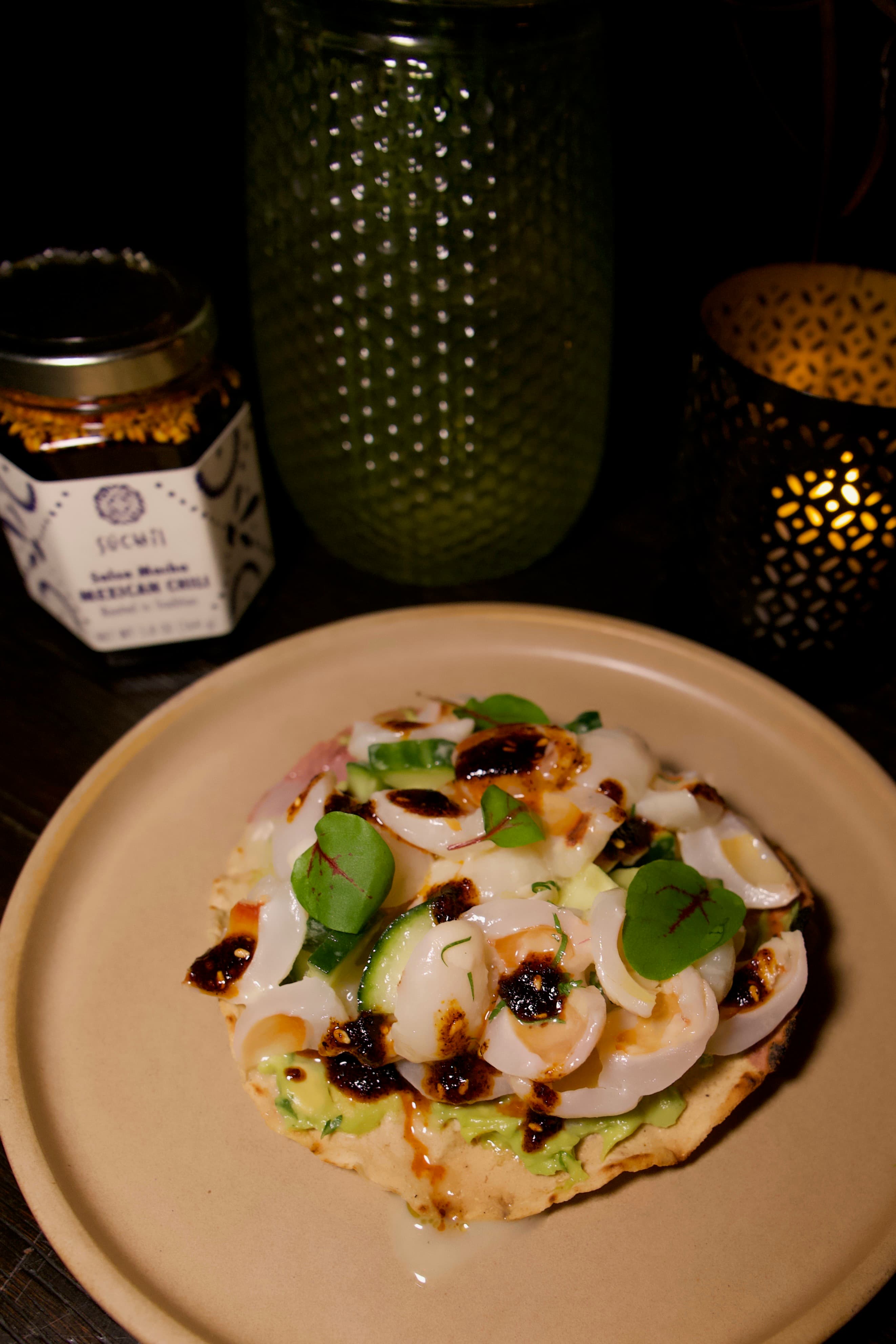 Seafood tostada drizzled with salsa macha beside a Súchil Made jar.
